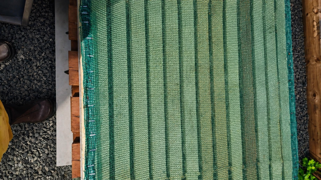 Green mesh screen board stapled to a wooden frame, used to unite two colonies over a screen